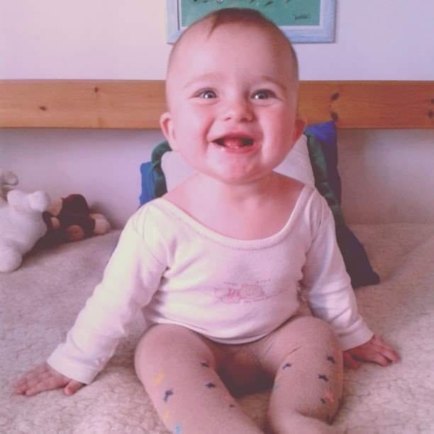 Jeune enfant souriant assis sur un lit